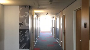 A hotel corridor with a long hallway, doors on both sides, and a patterned carpet.