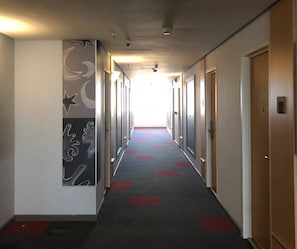 A hotel corridor with a long hallway, doors on both sides, and a patterned carpet.