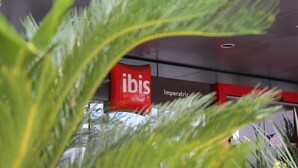 A hotel sign with the name "ibis Hotels" and a part of the interior with a red accent wall and a sign reading "Imperatriz".