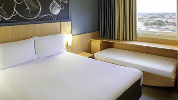 Une chambre d’hôtel avec un grand lit, une table de chevet, un petit bureau, une fenêtre avec des rideaux et une œuvre d’art accrochée au mur.