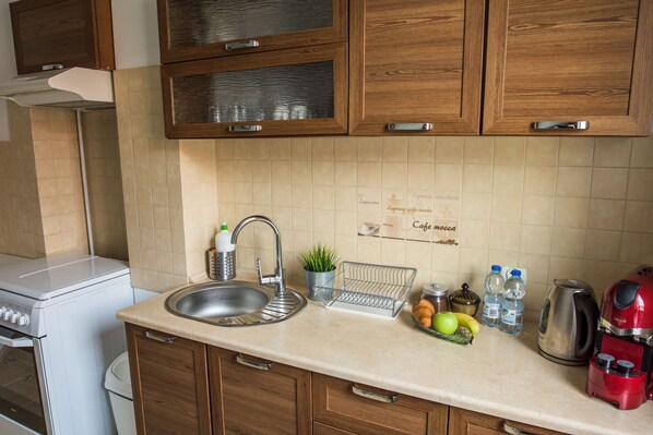 A kitchen with wooden cabinets, a stainless steel sink, a coffee maker, and a kettle. - Apartamenty Centrum (Koszalin)