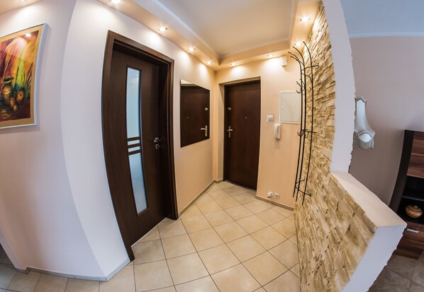 Un pasillo con dos puertas de madera, un muro decorativo de piedra y piso de baldosas.
