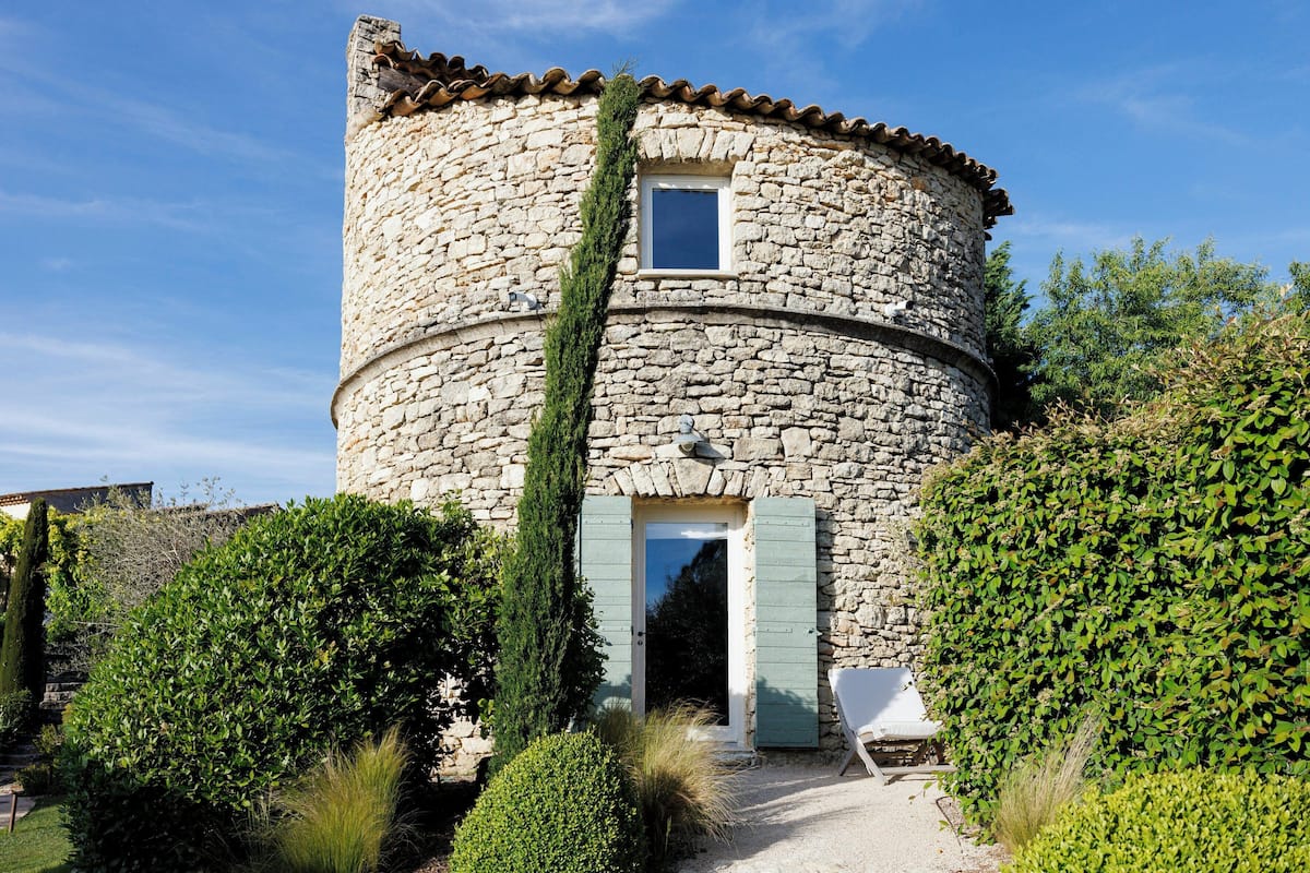 Una torre de piedra con una ventana y una puerta, rodeada de vegetación.