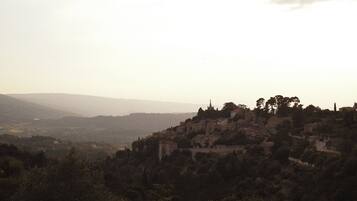 A town with historic buildings on a hill, surrounded by trees and hills in the background.