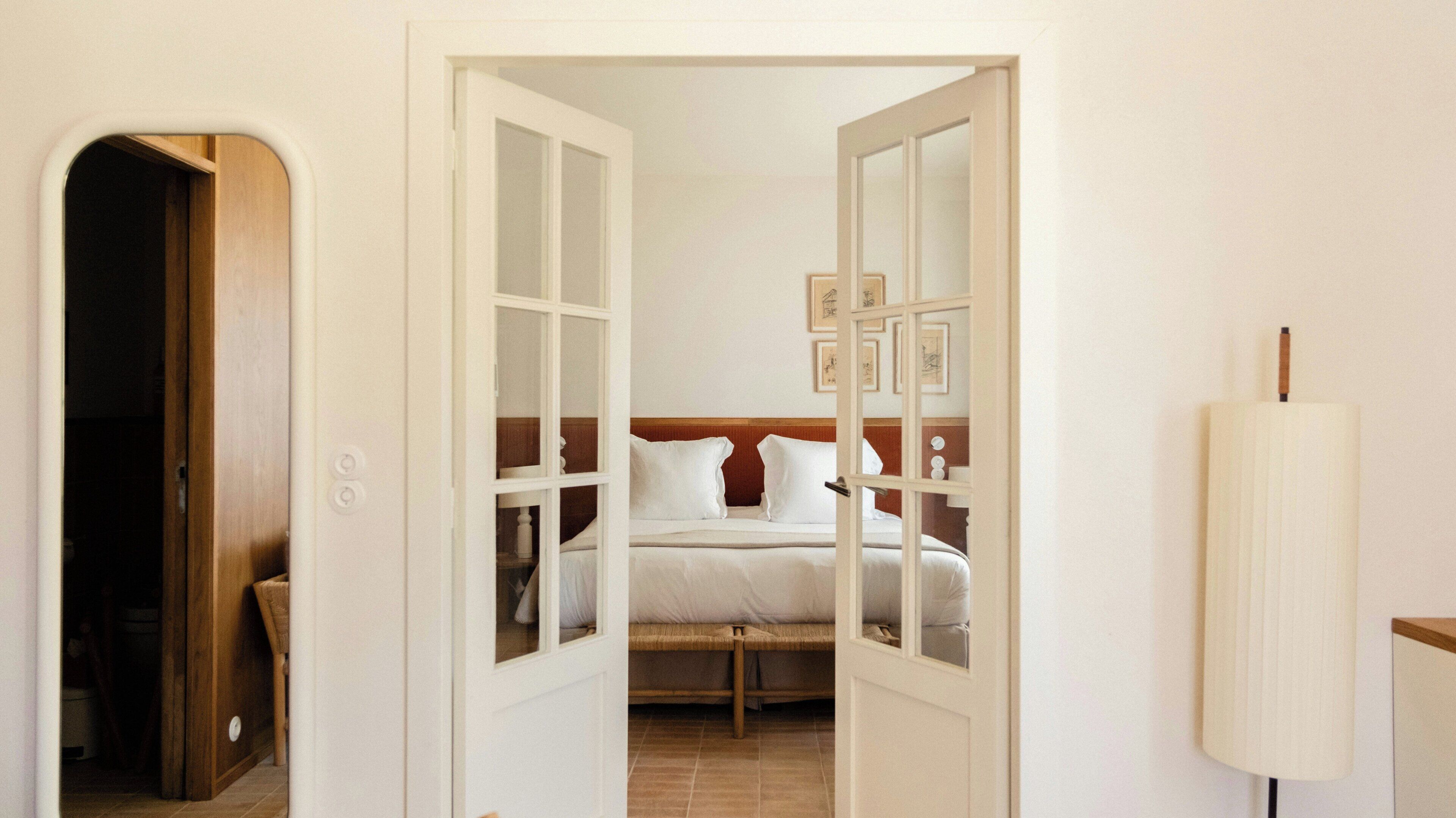 A bedroom with a bed, a wooden door, and a white lamp.