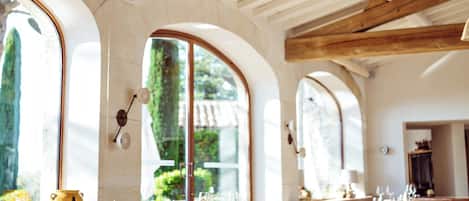 Un amplio comedor con mobiliario de madera y grandes ventanales de arco que dejan entrar luz natural.