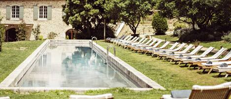 A swimming pool with lounge chairs and a building in the background.