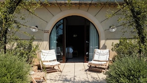 A hotel entrance with a large arched doorway, two white cushioned chairs, and a small table. - Capelongue, a Beaumier Hotel (Bonnieux)