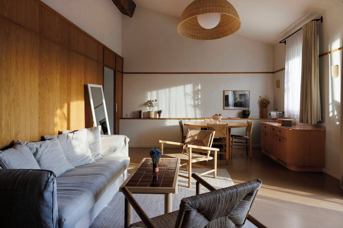 Una sala de estar moderna con un sofá, sillas, una mesa de comedor y una zona de cocina.