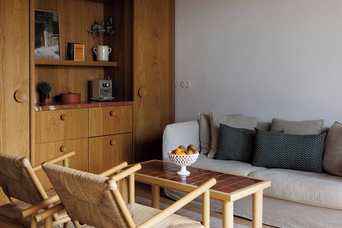 Una sala de estar con un aparador de madera, un sofá, una mesa de centro y una silla de mimbre.