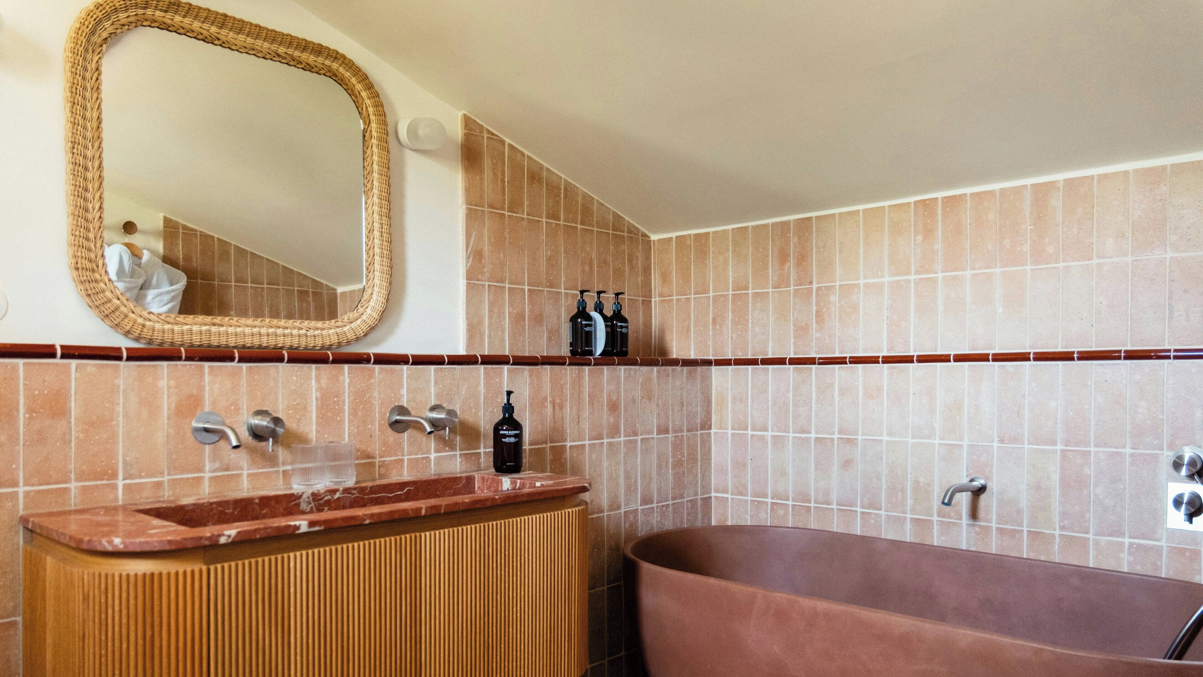 A bathroom with a freestanding bathtub, a vanity with a marble countertop, a large mirror, and a shelf with toiletries.