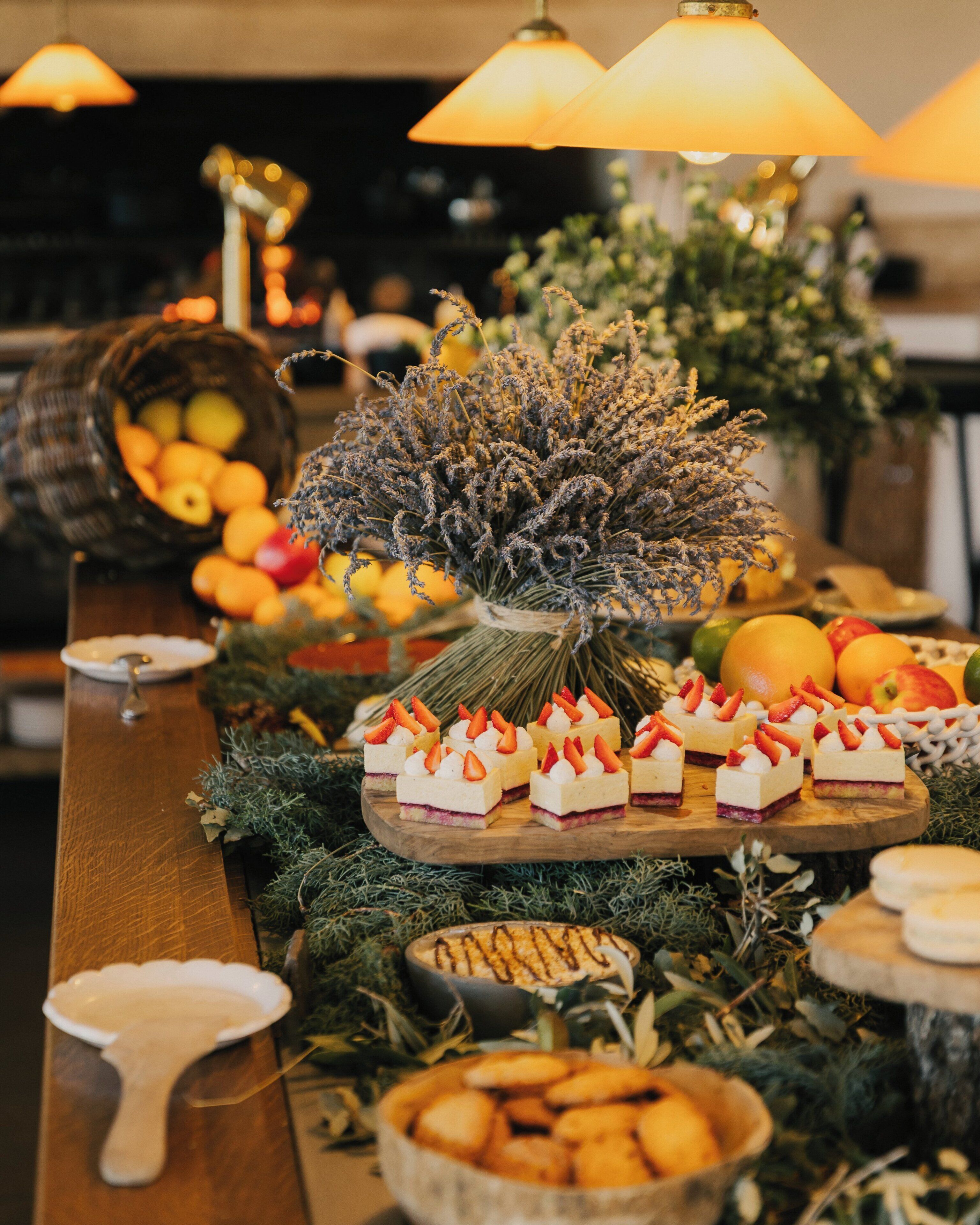 A buffet table with various food items, including desserts and fruits, arranged on a wooden board.