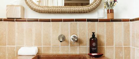 A bathroom with a marble sink, two faucets, a bottle of body lotion, and a towel.