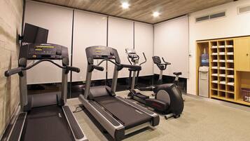 Ein Fitnessstudio mit Laufbändern, Crosstrainern und einem Ergometer.