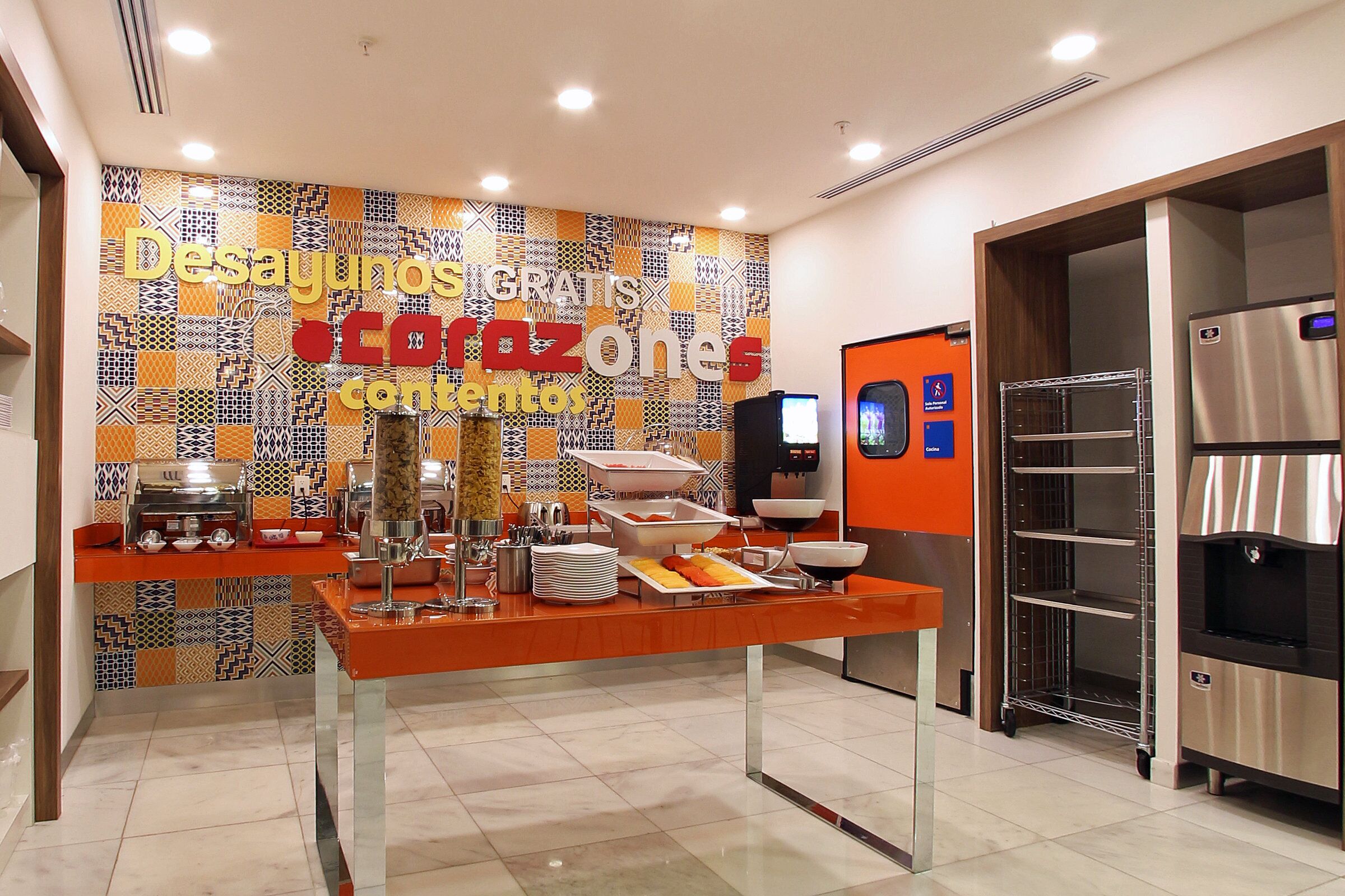 A buffet area with a colorful patterned wall and a stainless steel refrigerator.