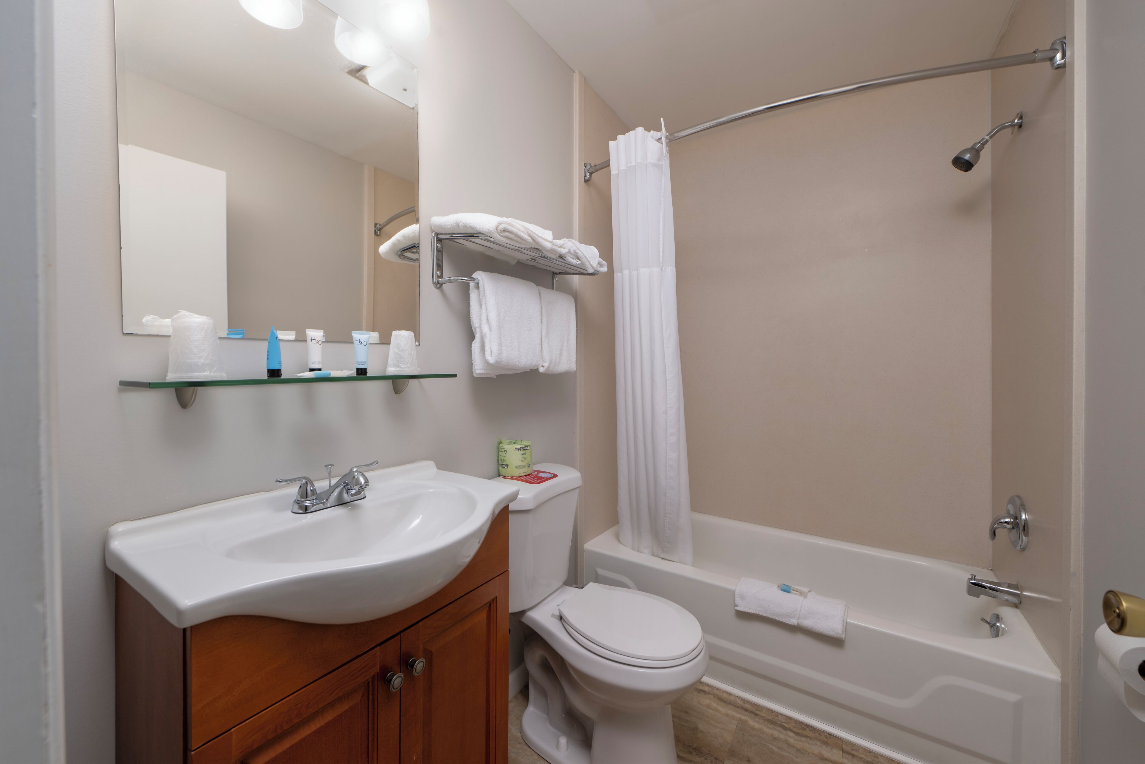 A bathroom with a sink, mirror, toilet, and bathtub.