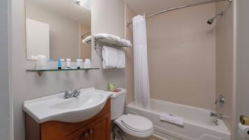 A bathroom with a sink, mirror, toilet, and bathtub.