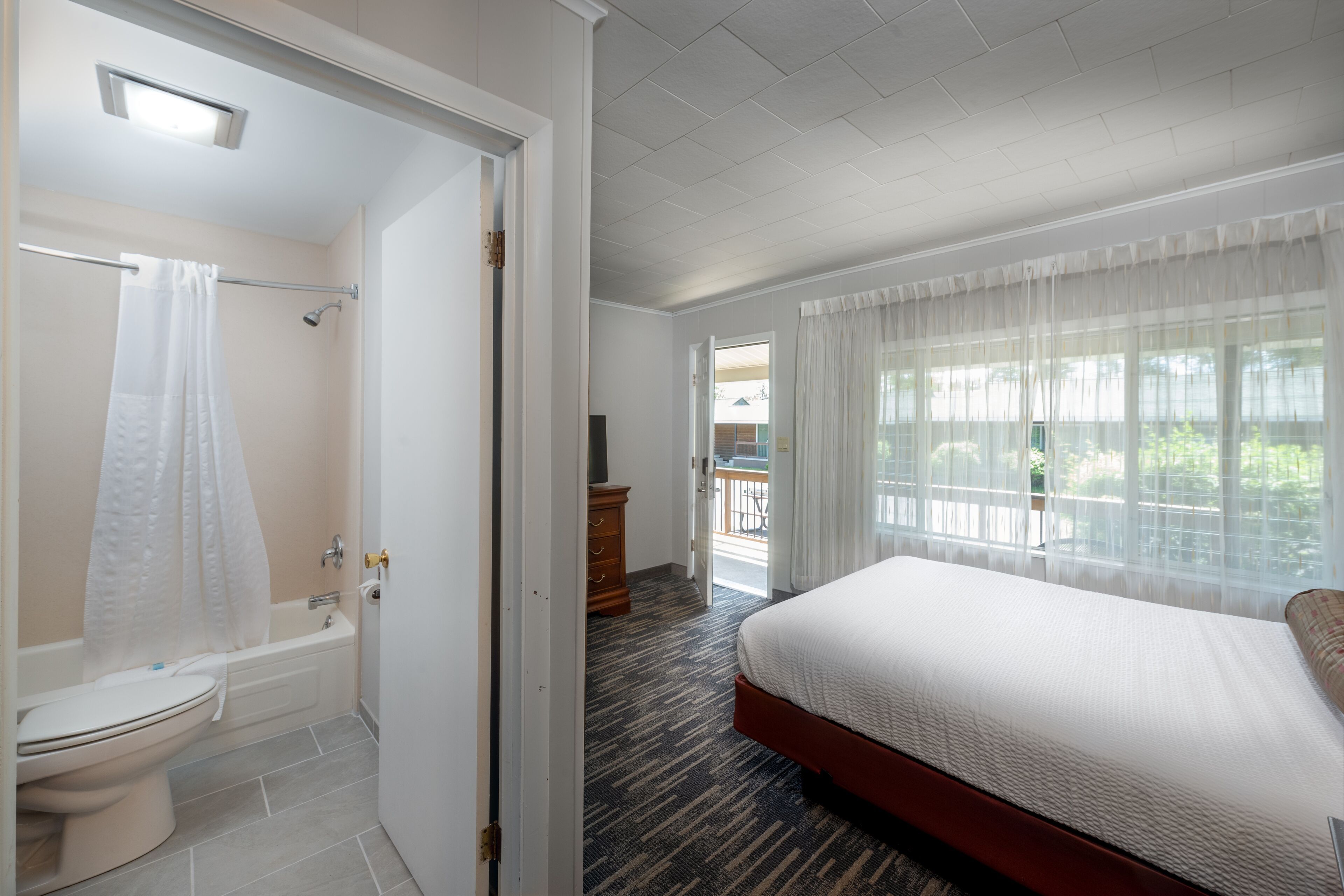 Ein Hotelzimmer mit Bad, einem Bett, einem Schminktisch und Blick ins Freie.