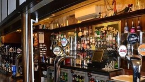 A bar area with multiple beer taps and a variety of liquor bottles. - The Queens Head Hotel (Buxton)