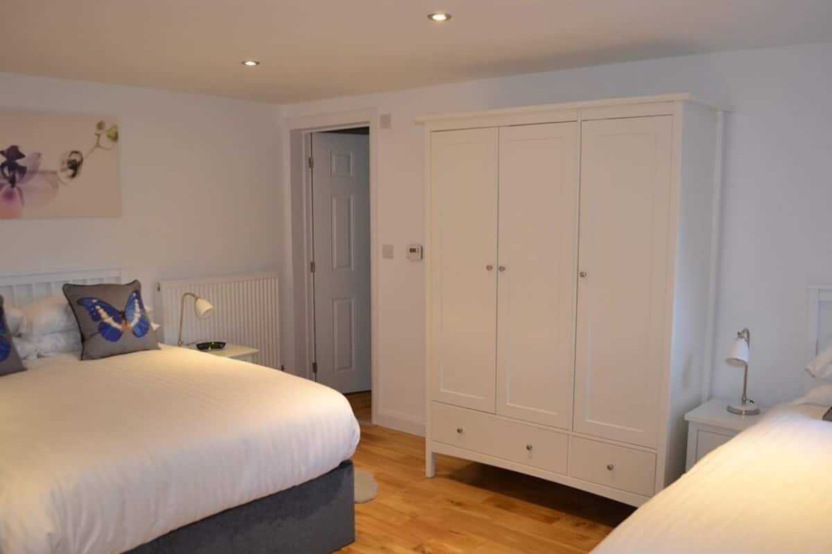 A bedroom with a large bed, a wardrobe, and a bedside table.
