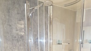 A glass-enclosed shower with a chrome finish, a white sink, and a mirror. - The Queens Head Hotel (Buxton)