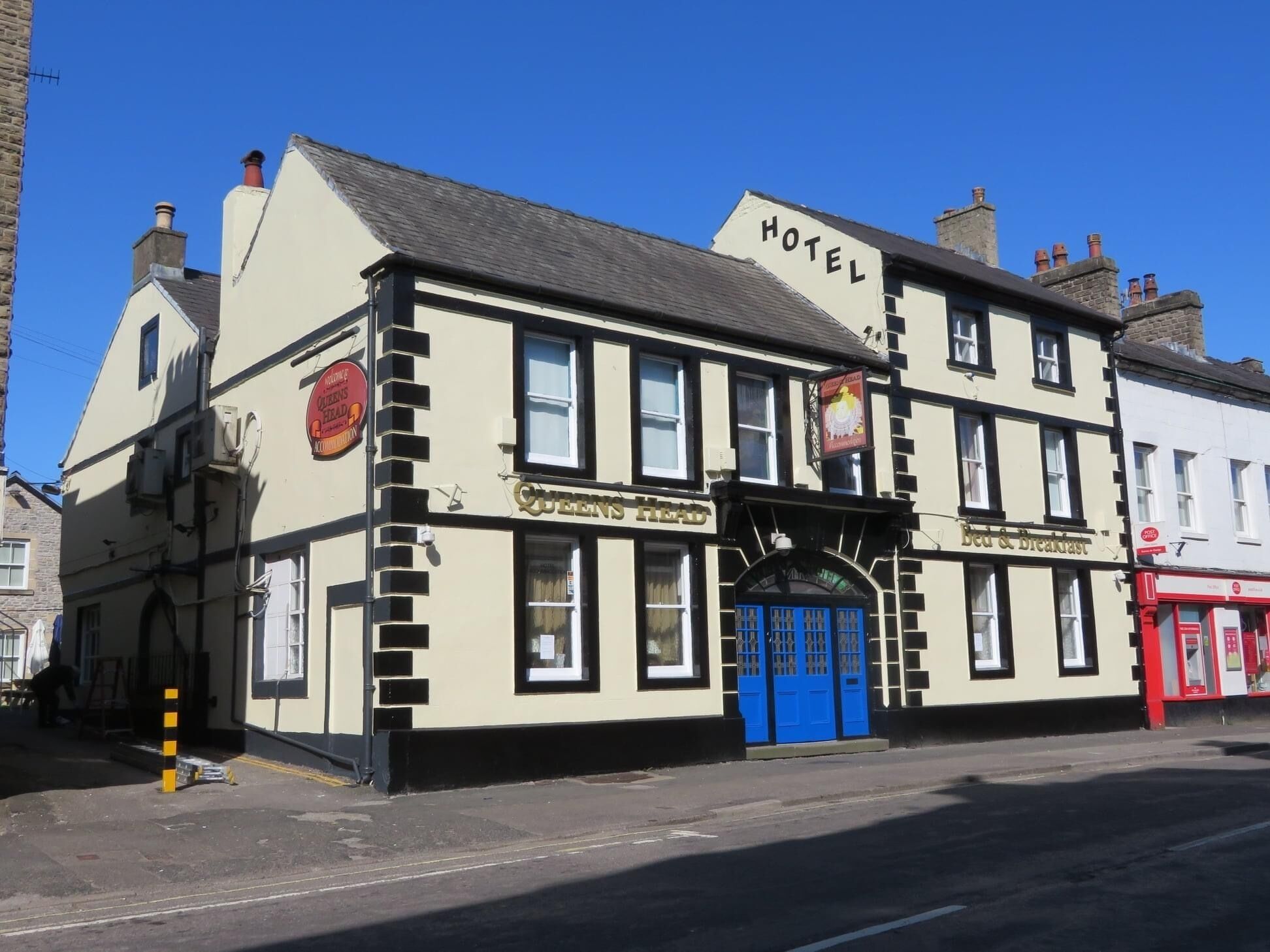 Un edificio tradicional con un letrero que dice "HOTEL" y "QUEENS HEAD" en la fachada.