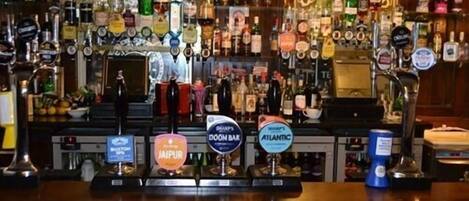 A bar with multiple taps and a variety of liquor bottles.