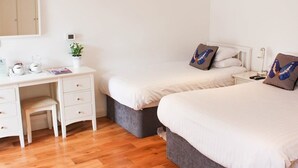 A bedroom with two single beds, a desk with a chair, a small bedside table, and a nightstand. - The Queens Head Hotel (Buxton)