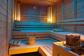 Una sauna de madera con bancos, un balde y un recipiente a lunares.