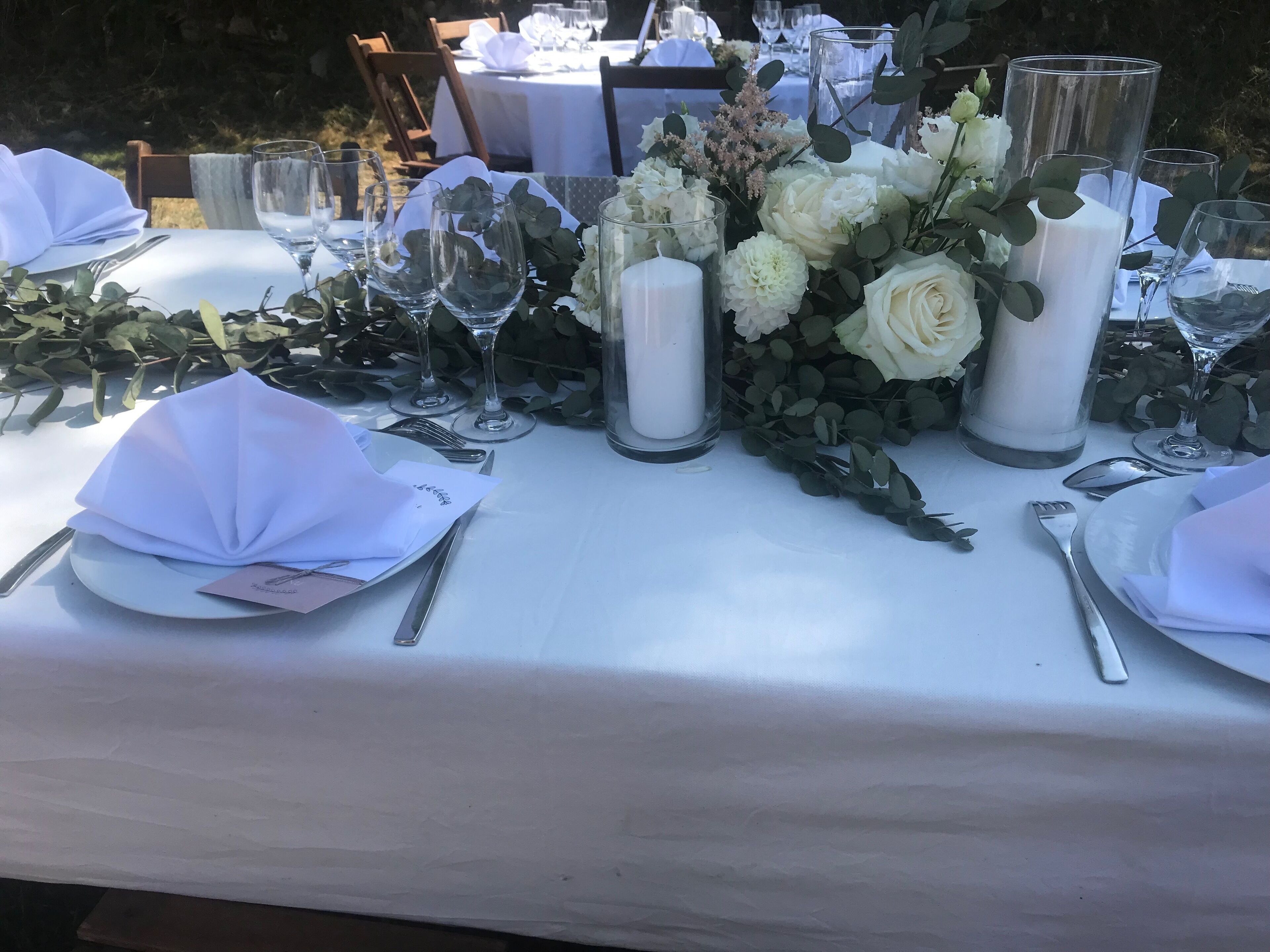 A table set for a formal event with white tablecloths, glassware, and floral centerpieces.
