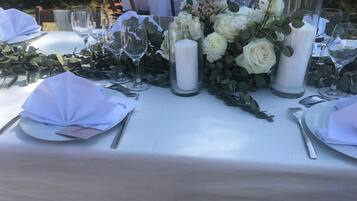 A table set for a formal event with white tablecloths, glassware, and floral centerpieces.