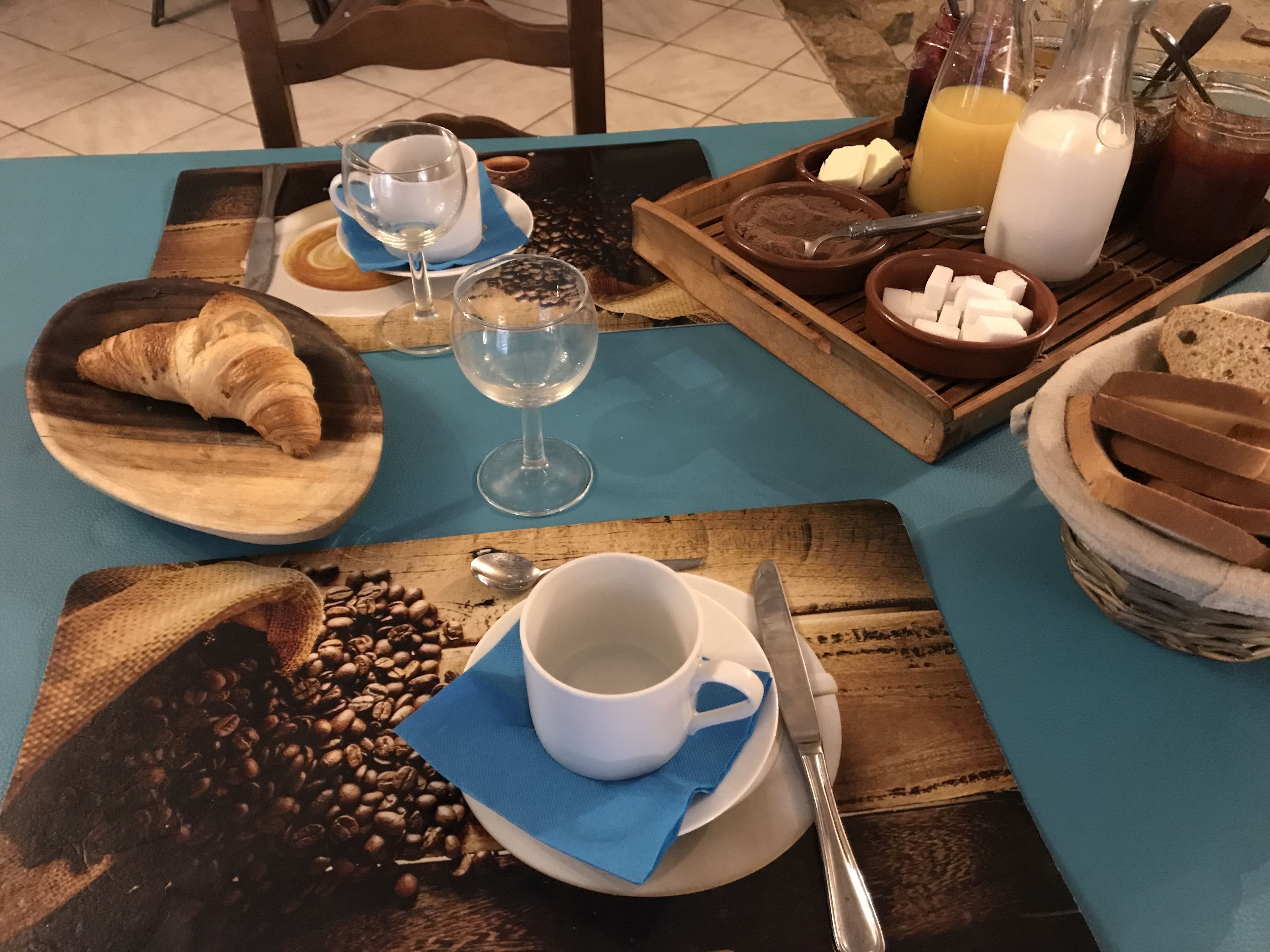 A breakfast table with croissants, coffee, milk, and juice.