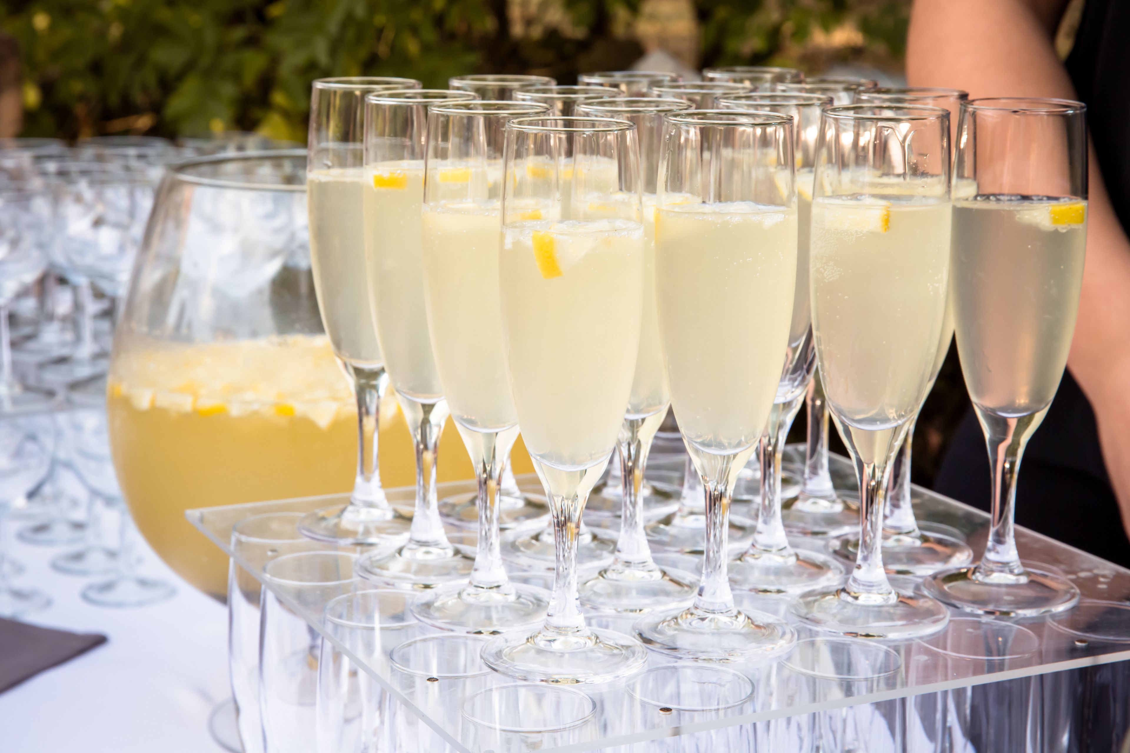 Een dienblad met champagneglazen en een grote karaf champagne erachter.