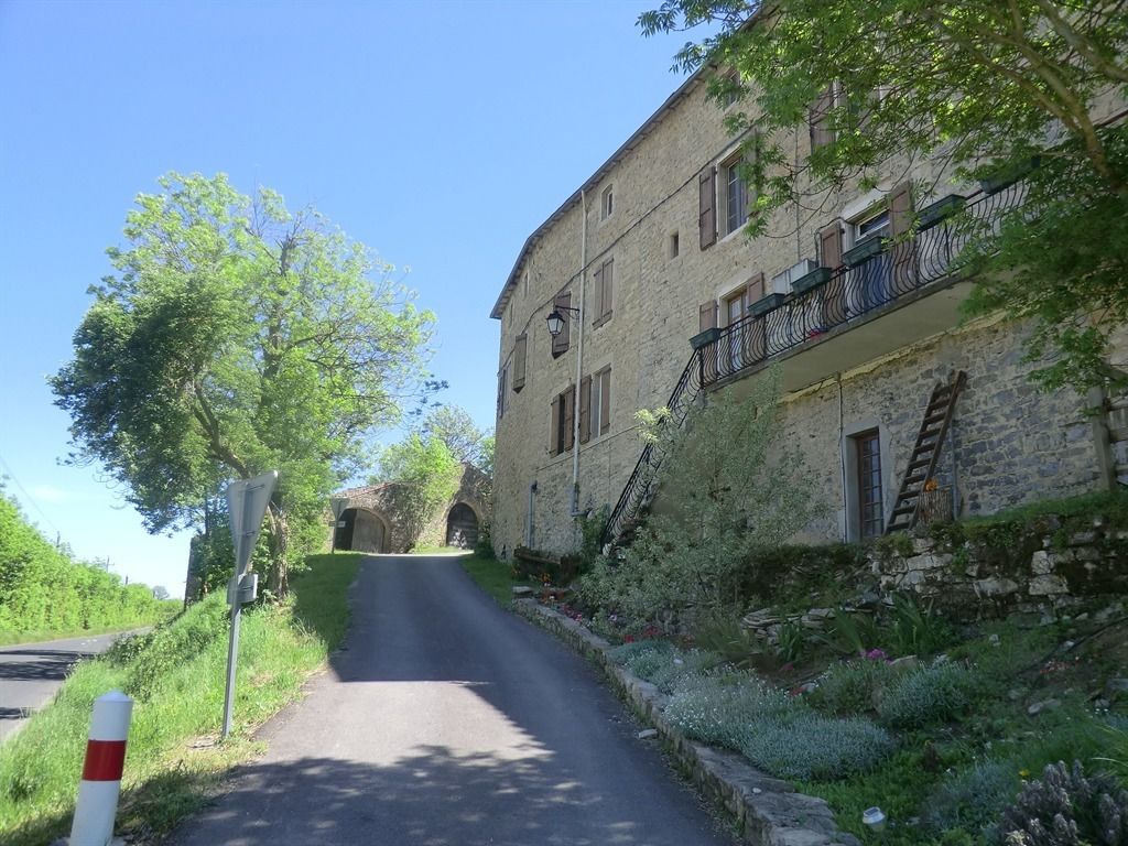 A narrow road leading to a stone building with a balcony.