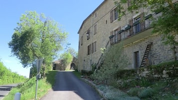 A narrow road leading to a stone building with a balcony.