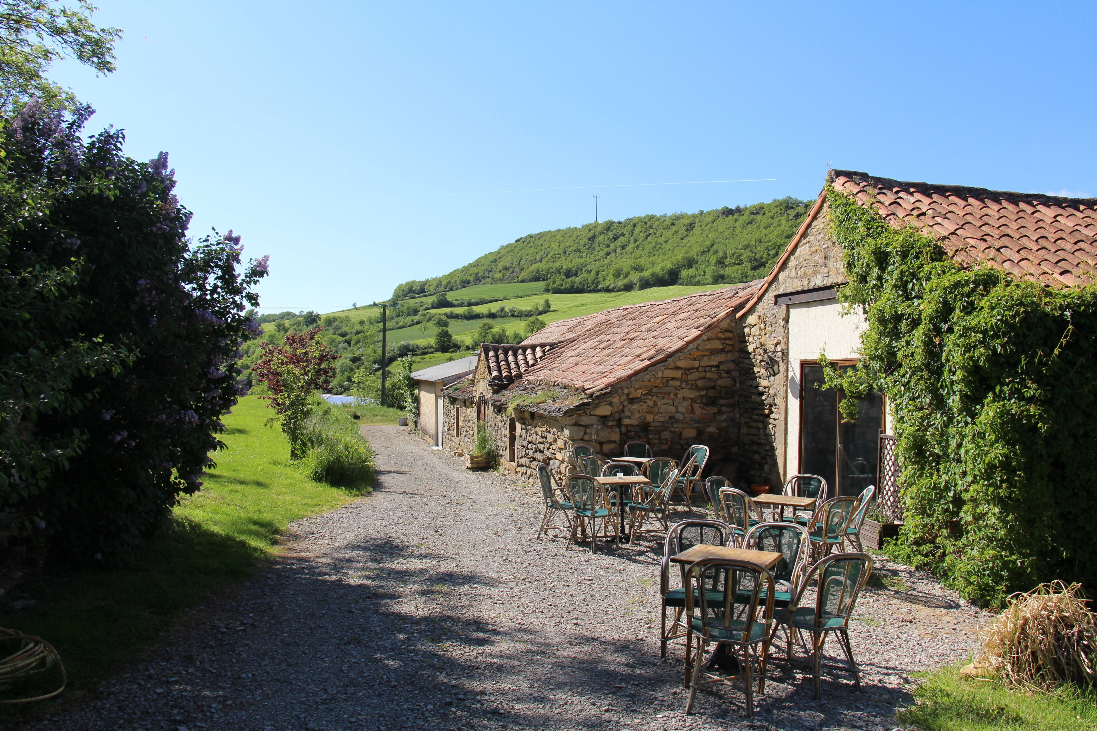 A rustic stone building with a gravel path leading to outdoor seating.