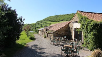 A rustic stone building with a gravel path leading to outdoor seating.