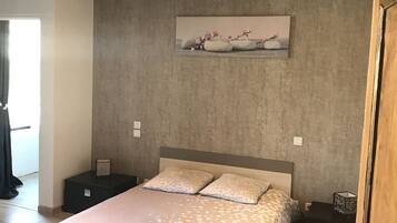 A bedroom with a bed, two bedside tables, a painting on the wall, and a wooden ceiling.