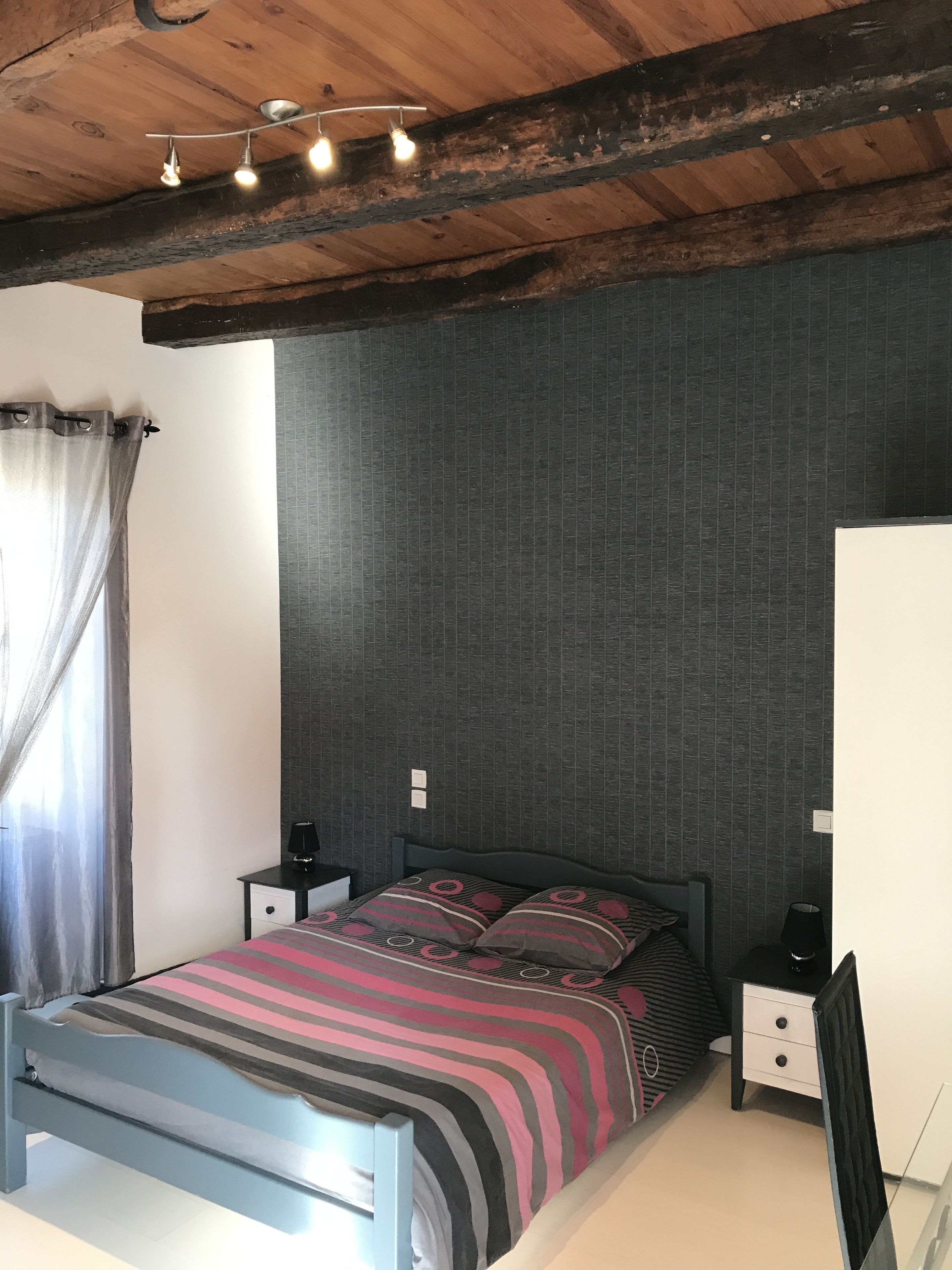 Ein Schlafzimmer mit einem Bett, Nachttischen, einer Lampe und einer Deckenleuchte.