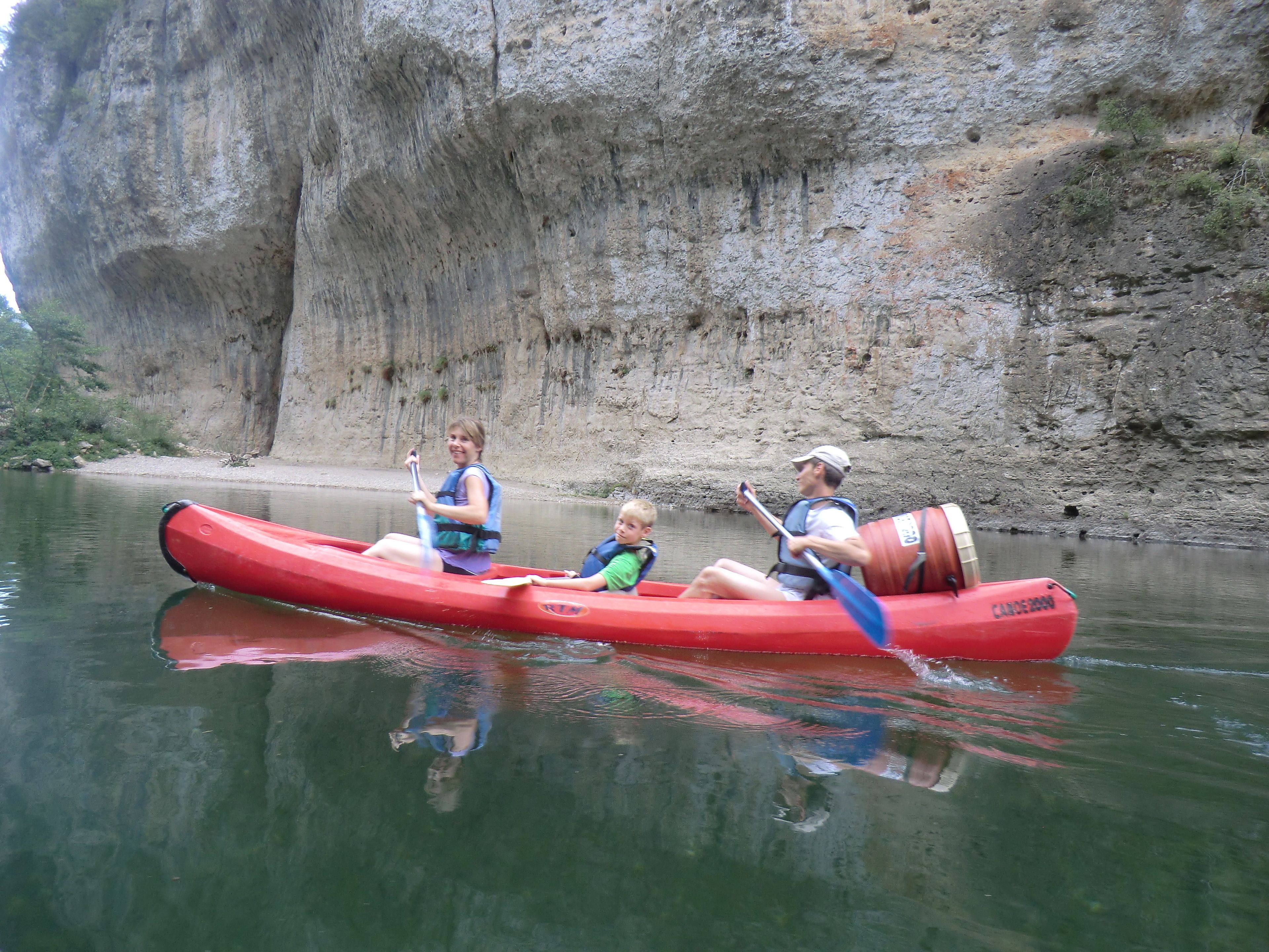 Un canoa rosso su acqua calma, con una scogliera rocciosa sullo sfondo.