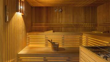 Una sauna in legno con panche, un catino e stufe a parete.