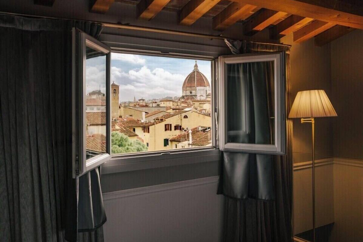A room with a window overlooking a cityscape, including a prominent dome building.