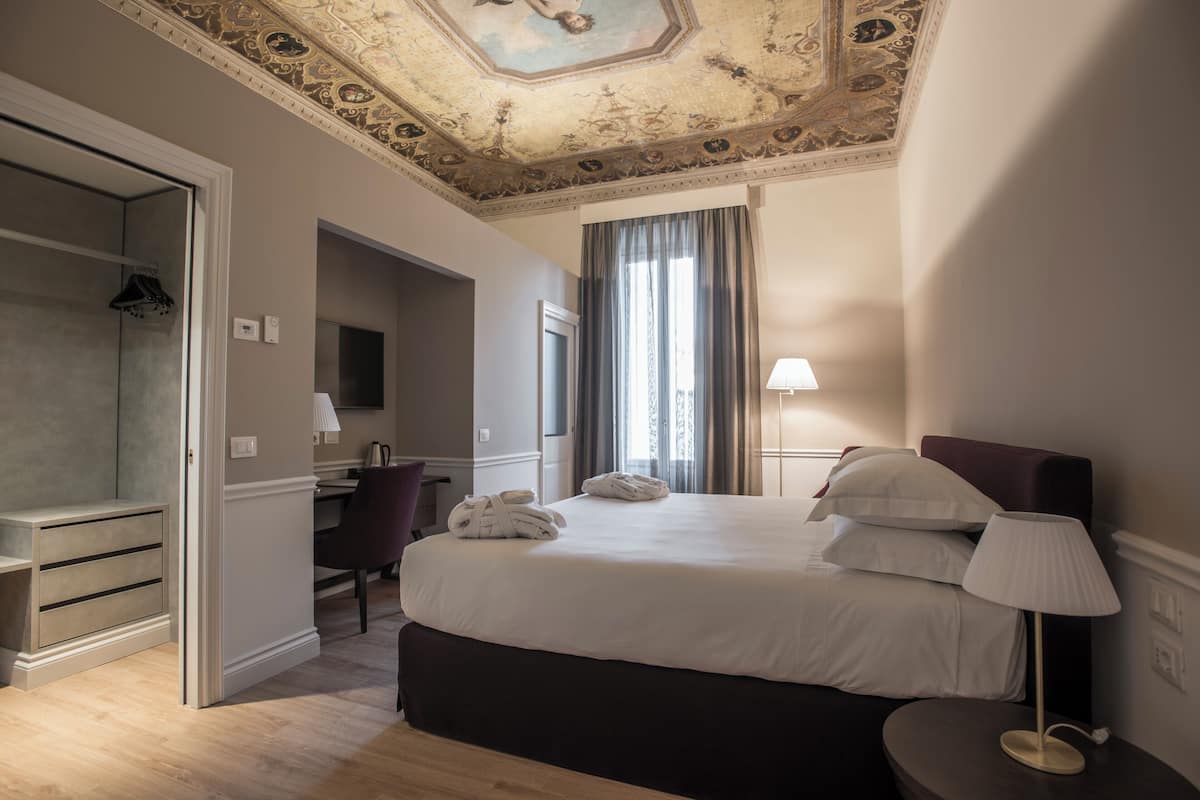Une chambre d’hôtel comprenant un lit, un bureau, une chaise, une armoire et une salle de bain.