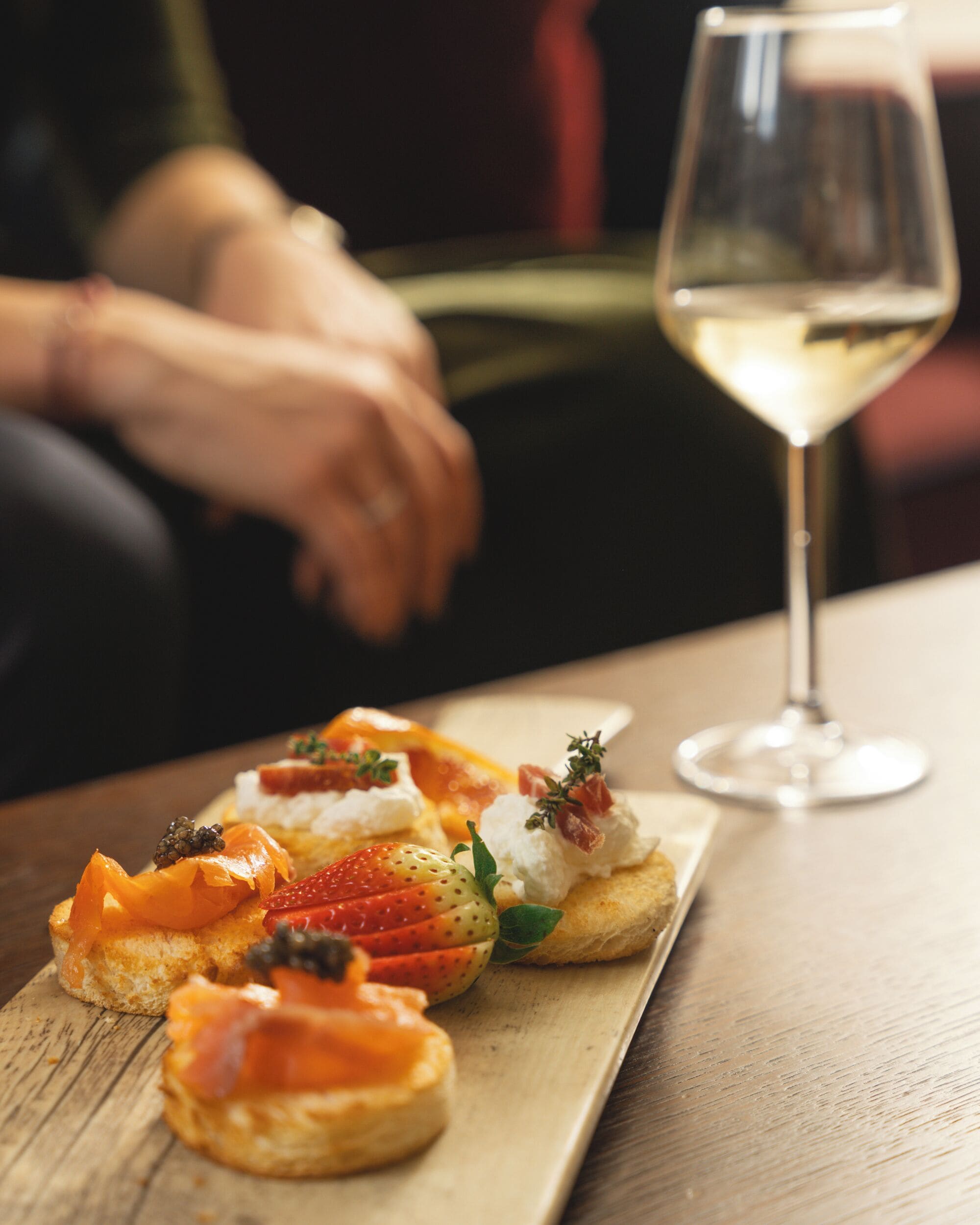 Un tavolo di legno con un piatto di cibo e un bicchiere di vino bianco.