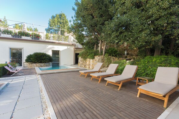 A wooden deck with lounge chairs and a swimming pool. - Palazzo Castri 1874 Spa & Garden (Florence)