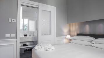 A hotel room with a large bed, a walk-in closet, a mirror, and a bedside lamp.