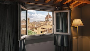 A room with a window overlooking a cityscape, featuring a dome and buildings. - Palazzo Castri 1874 Spa & Garden (Florence)