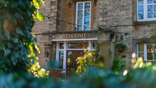 Un edificio de piedra con un cartel que dice “WELCOME” sobre la entrada.
