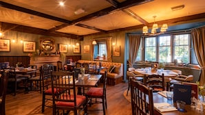 Un restaurante con mobiliario de madera, ventanas amplias y chimenea.