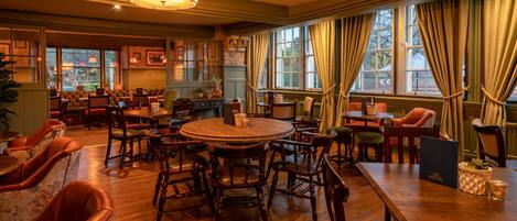 Un restaurant chaleureux, avec des meubles en bois, de grandes fenêtres et un lustre.